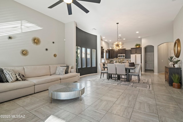 living room featuring arched walkways, ceiling fan with notable chandelier, and recessed lighting