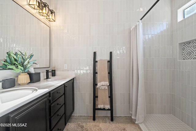 full bath with a tile shower, double vanity, and a sink