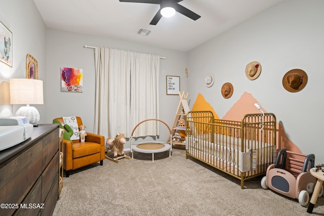 bedroom featuring a nursery area, carpet, visible vents, and ceiling fan