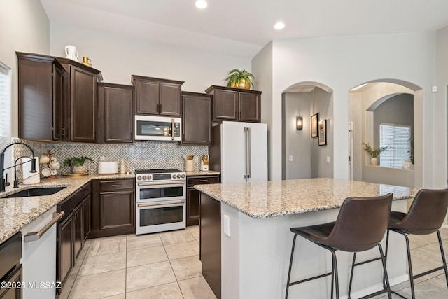 kitchen with white appliances, a sink, decorative backsplash, and light stone countertops