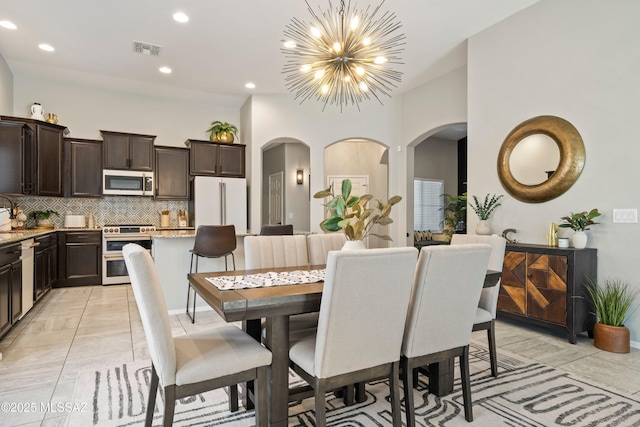 dining area with arched walkways, a notable chandelier, light tile patterned floors, recessed lighting, and visible vents