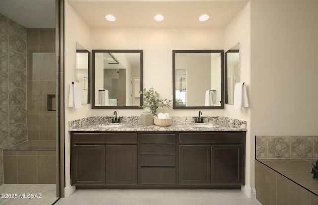bathroom featuring double vanity, tile patterned floors, tiled shower, and a sink