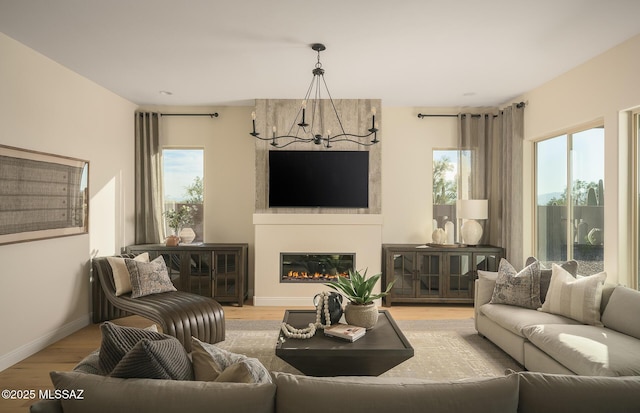 living room featuring baseboards, a wealth of natural light, wood finished floors, and a notable chandelier