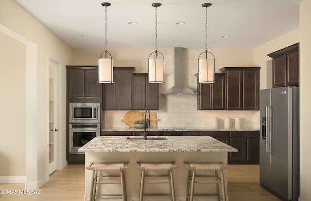 kitchen with dark brown cabinetry, a sink, wall chimney exhaust hood, stainless steel appliances, and backsplash