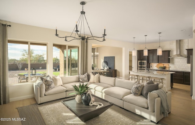 living area featuring light wood-style floors, baseboards, and a notable chandelier