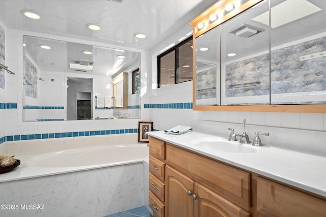 bathroom featuring vanity, visible vents, decorative backsplash, tile walls, and a bath