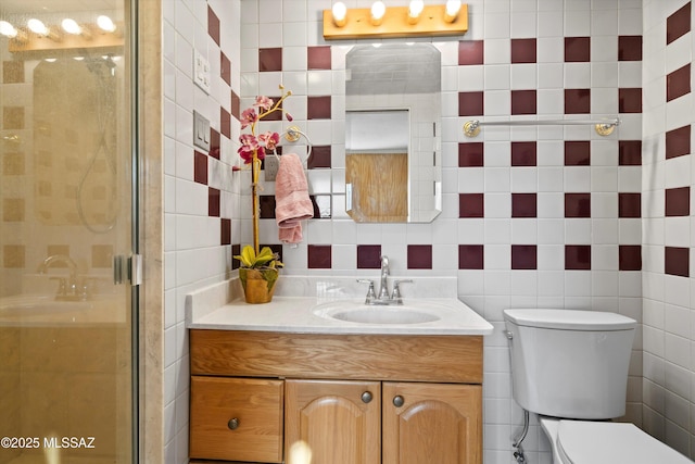 bathroom featuring vanity, toilet, tile walls, and a shower stall