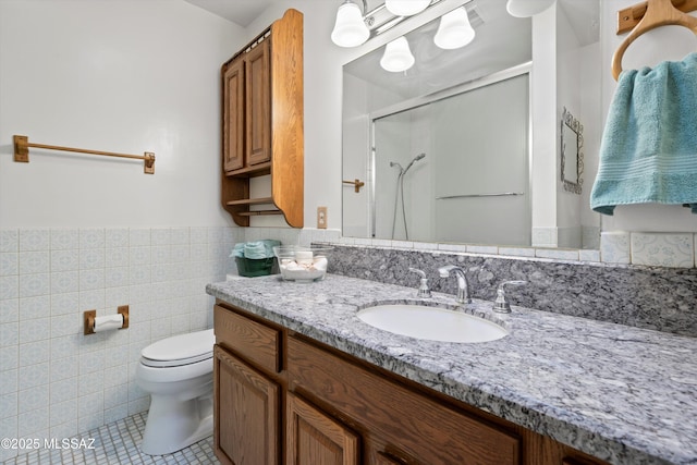 bathroom featuring tile patterned flooring, a wainscoted wall, toilet, a stall shower, and tile walls