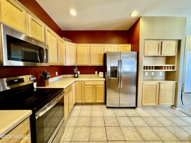 kitchen featuring light brown cabinetry, a textured ceiling, stainless steel appliances, light countertops, and light tile patterned floors
