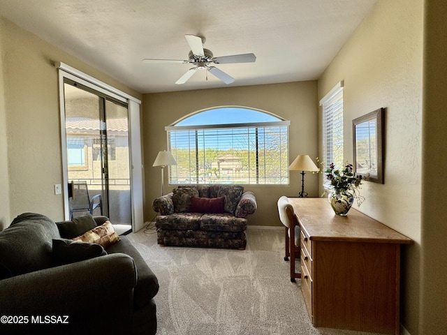 living room with carpet, baseboards, a textured wall, and ceiling fan
