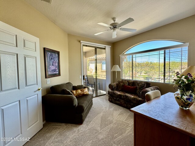 living room featuring light colored carpet, ceiling fan, and a textured ceiling