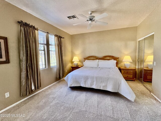 carpeted bedroom featuring a ceiling fan, baseboards, visible vents, a closet, and a textured ceiling