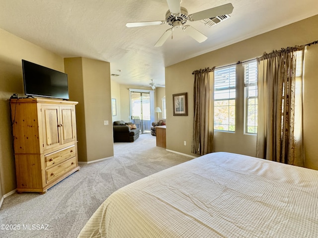bedroom with visible vents, baseboards, light colored carpet, a textured ceiling, and a ceiling fan