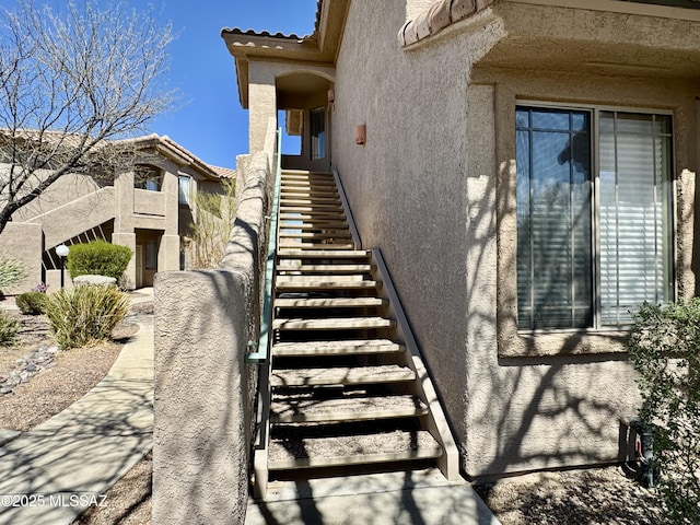 view of side of home with a tiled roof, stairway, and stucco siding