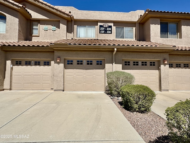 multi unit property featuring stucco siding, driveway, an attached garage, and a tiled roof