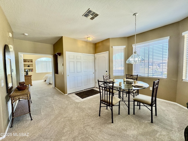 carpeted dining area with baseboards, visible vents, and a textured ceiling