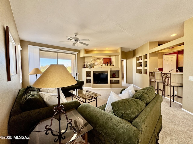 living room featuring a ceiling fan, carpet, baseboards, and a textured ceiling