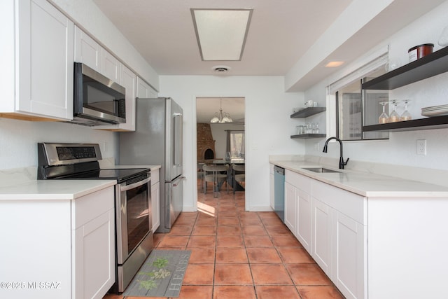 kitchen featuring white cabinets, stainless steel appliances, light countertops, open shelves, and a sink