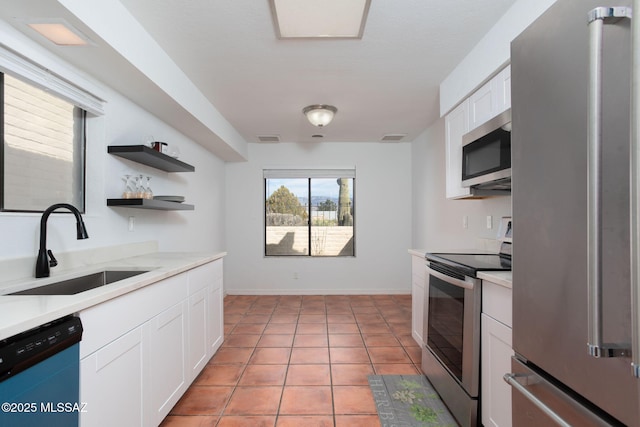 kitchen featuring open shelves, stainless steel appliances, light countertops, white cabinets, and a sink