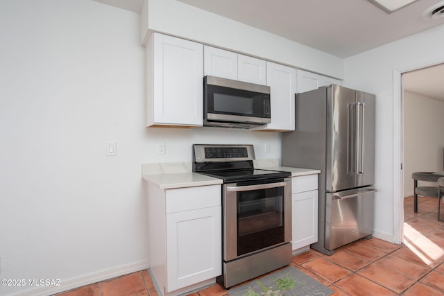 kitchen with appliances with stainless steel finishes, light tile patterned floors, light countertops, and white cabinetry