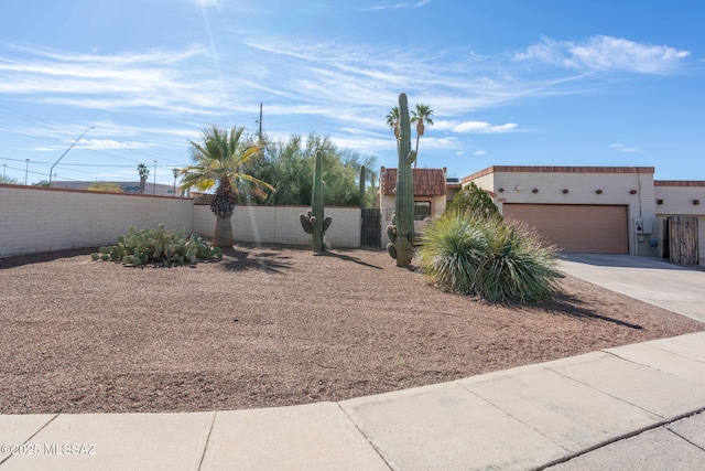 view of front facade with a tile roof, stucco siding, concrete driveway, an attached garage, and fence