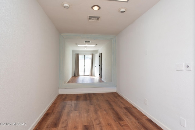 hallway featuring dark wood-style flooring, visible vents, and baseboards