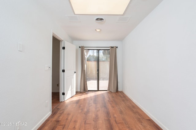 spare room with visible vents, baseboards, and wood finished floors