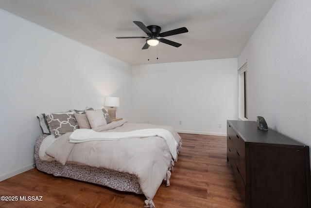 bedroom featuring a ceiling fan, baseboards, and dark wood-type flooring