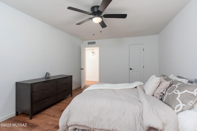 bedroom with light wood-style floors, baseboards, visible vents, and a ceiling fan