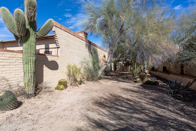 view of property exterior with brick siding and fence