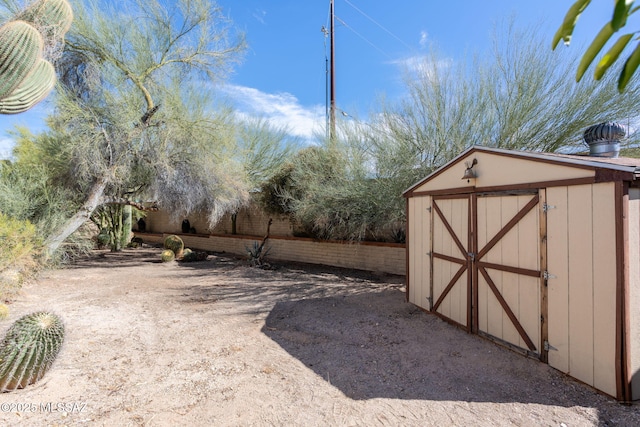 view of yard featuring a shed, an outdoor structure, and fence