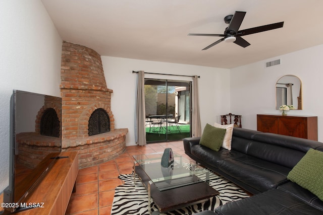 living area with a brick fireplace, ceiling fan, light tile patterned floors, and visible vents