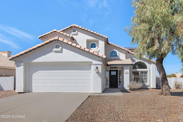 mediterranean / spanish-style house featuring a garage, driveway, a tiled roof, and stucco siding