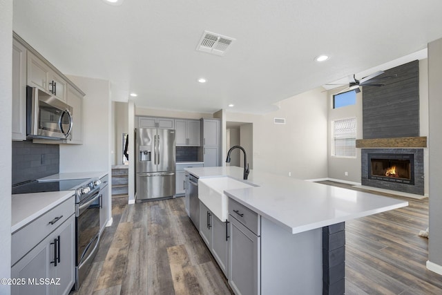 kitchen featuring stainless steel appliances, a spacious island, a sink, visible vents, and open floor plan