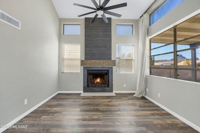 unfurnished living room featuring dark wood-type flooring, a large fireplace, visible vents, and baseboards