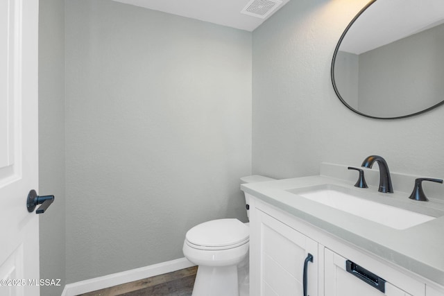 bathroom with toilet, wood finished floors, vanity, visible vents, and baseboards