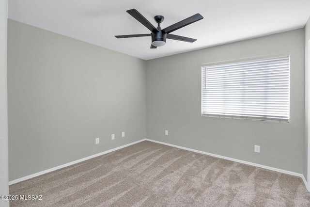 empty room with carpet flooring, a ceiling fan, and baseboards