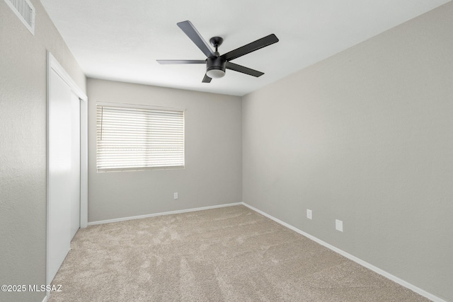 spare room featuring a ceiling fan, light colored carpet, visible vents, and baseboards