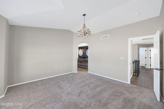 unfurnished room with vaulted ceiling, visible vents, dark carpet, and an inviting chandelier