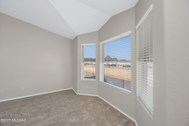 spare room featuring carpet, vaulted ceiling, and baseboards