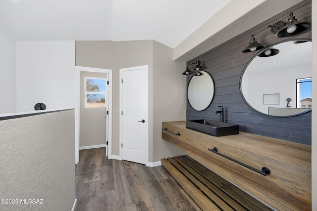 bathroom featuring baseboards, wood finished floors, vanity, and a healthy amount of sunlight