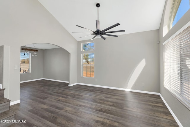 unfurnished living room featuring arched walkways, dark wood finished floors, and baseboards