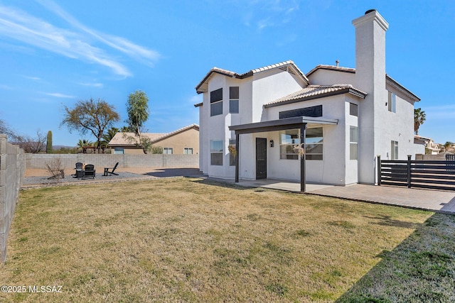 rear view of house featuring a yard, a patio, a chimney, stucco siding, and a fenced backyard