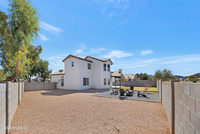 rear view of property with an outdoor fire pit, a patio area, a fenced backyard, and stucco siding