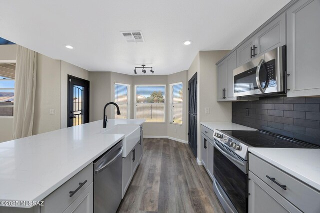 kitchen featuring visible vents, decorative backsplash, appliances with stainless steel finishes, gray cabinetry, and a sink