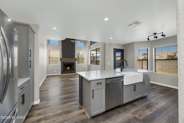 kitchen featuring open floor plan, stainless steel appliances, light countertops, and gray cabinetry