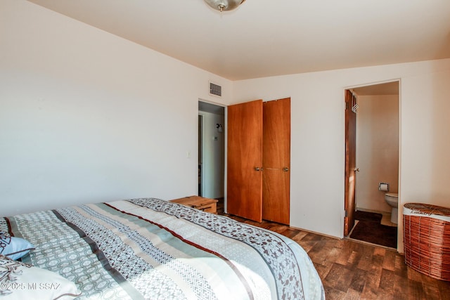 bedroom featuring visible vents, dark wood finished floors, and ensuite bathroom