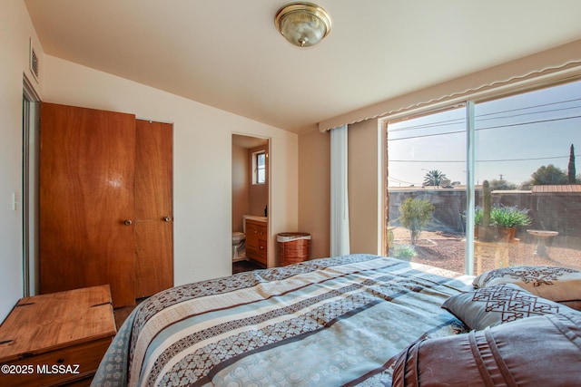 bedroom featuring lofted ceiling, visible vents, and ensuite bathroom