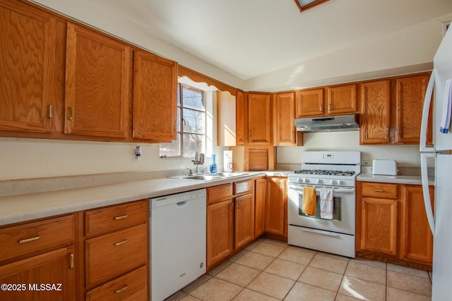 kitchen featuring white appliances, under cabinet range hood, light countertops, and a sink