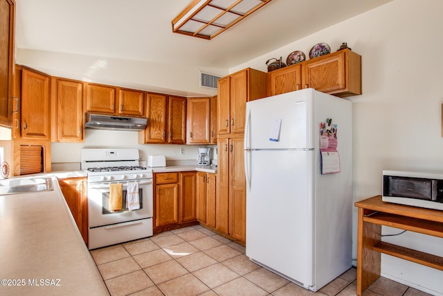 kitchen with light tile patterned floors, under cabinet range hood, white appliances, a sink, and light countertops